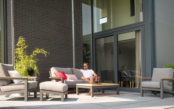 Een man zit lekker op een tuinbank.